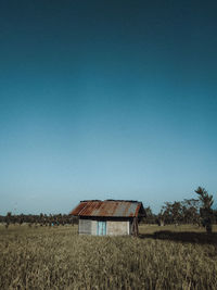 House on field against clear blue sky