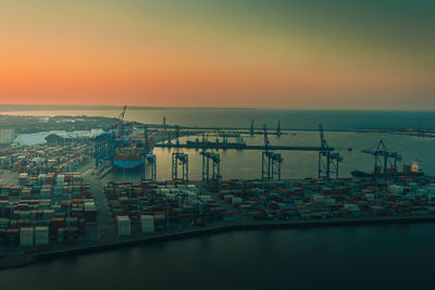 Commercial dock by sea against sky during sunset