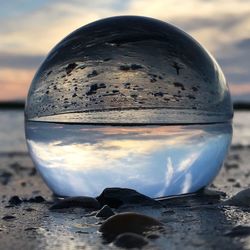 Close-up of crystal ball on beach against sky