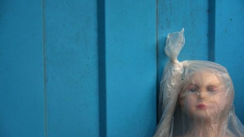 Close-up of abandoned doll wrapped in plastic against wall