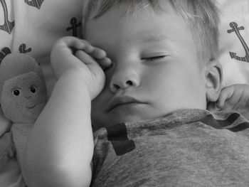 Close-up of boy rubbing eyes while sleeping on bed at home