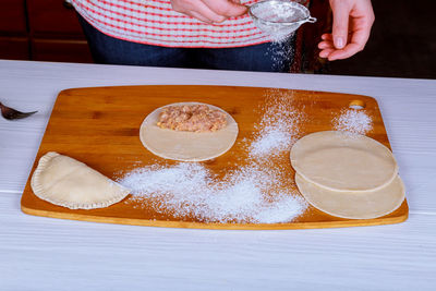 Cropped hands of woman preparing food on cutting board