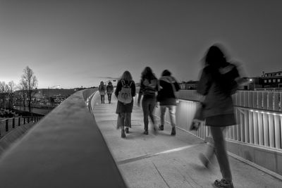 People walking on footpath in city against clear sky