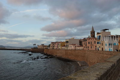 Buildings by sea against sky in city