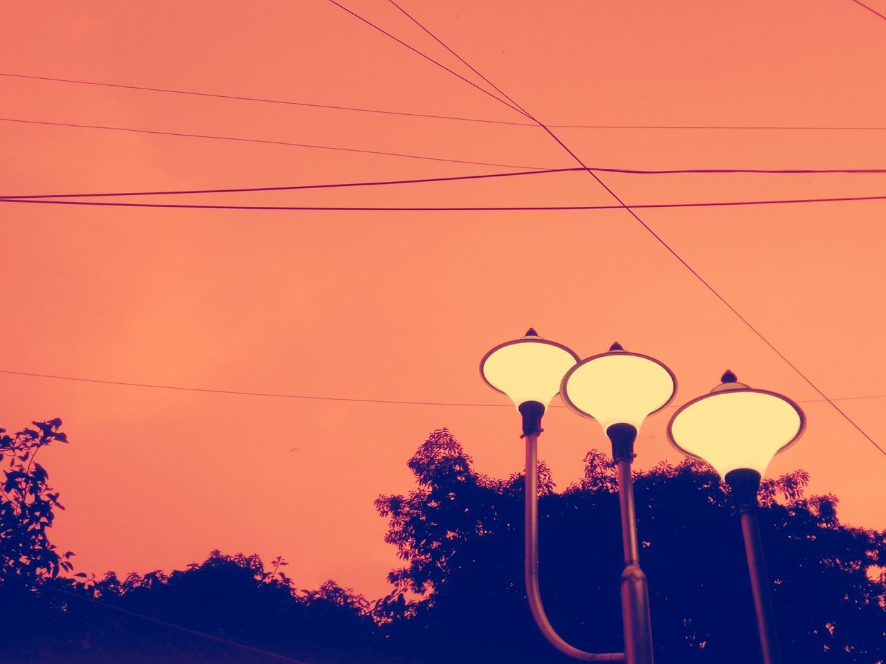 electricity, sunset, low angle view, power line, silhouette, lighting equipment, cable, orange color, power supply, street light, electricity pylon, technology, connection, fuel and power generation, sky, clear sky, electric light, illuminated, hanging, dusk