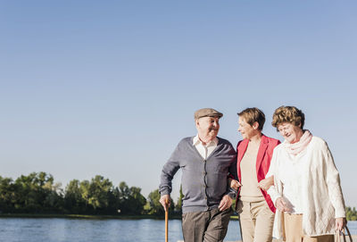 Parents strolling with their adult daughter at riverside strolling at riverside