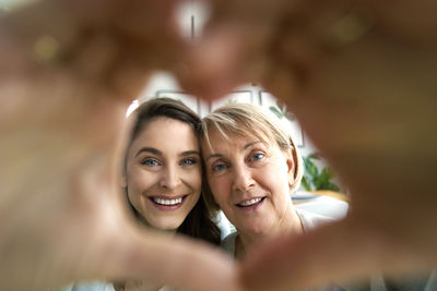 Portrait of mother and daughter making heart shape