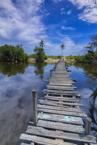 Pier over calm lake against sky