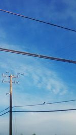 Low angle view of power lines against blue sky