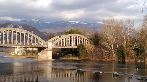 Arch bridge over river against cloudy sky