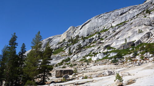 Low angle view of rocky mountains against clear blue sky