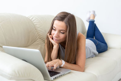 Young woman using mobile phone on sofa