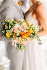 Midsection of couple holding flower bouquet