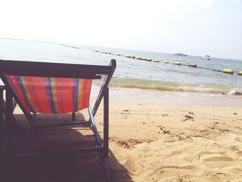 Empty chairs on beach against sky