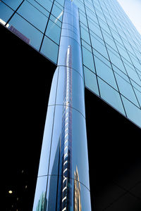 Low angle view of glass building against clear blue sky