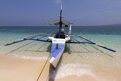 Catamaran on shore against clear sky