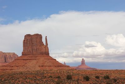 Rock formations on landscape against cloudy sky