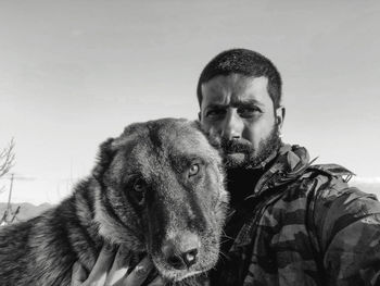 Portrait of man with dog against sky