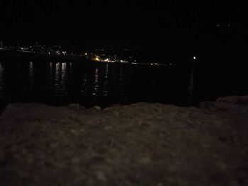 Illuminated beach against sky at night