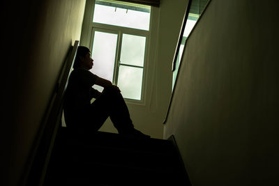 Side view of man sitting on staircase at home