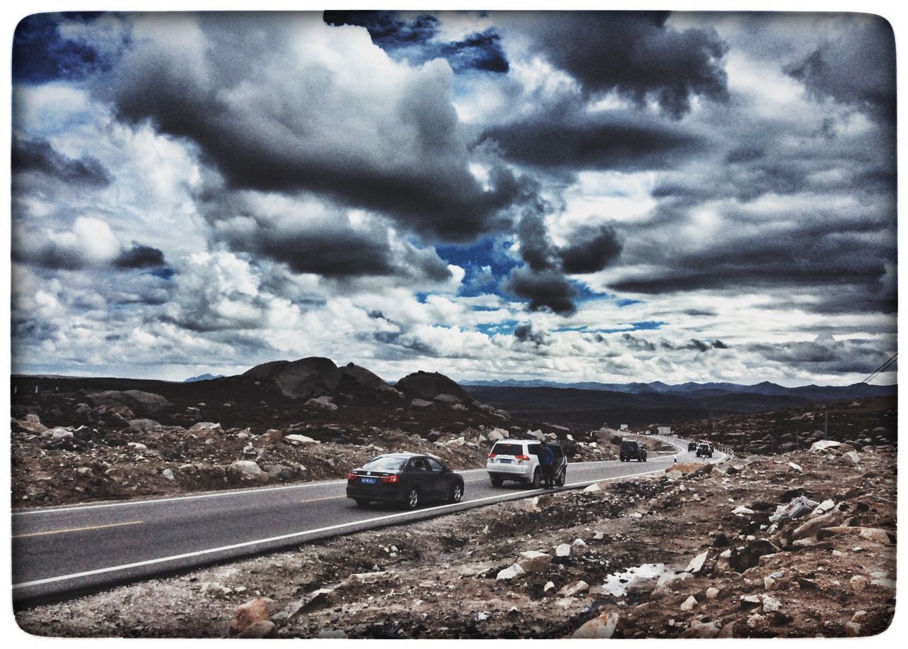 VIEW OF MOUNTAIN ROAD AGAINST CLOUDY SKY