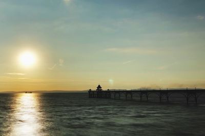 Silhouette of bridge over sea during sunset