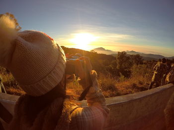 Rear view of woman photographing landscape  during sunset