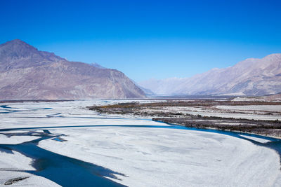 Scenic view of mountains against clear blue sky