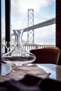 Close-up of glass vase on table against window at home