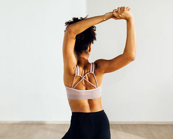 Rear view of woman with arms raised dancing in studio