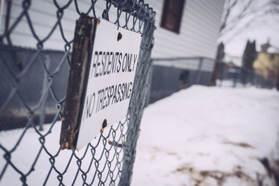 Close-up of sign on chainlink fence in snow