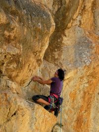 Woman with umbrella hanging on rock