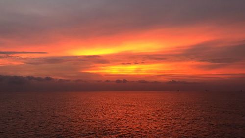 Scenic view of sea against dramatic sky during sunset