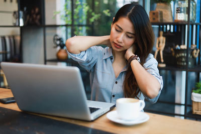 Young woman using mobile phone while sitting on table