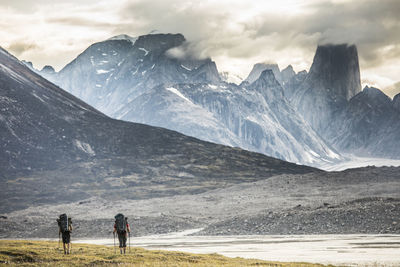 Rear view of people on snowcapped mountain against sky