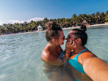 Couple kissing in swimming pool against trees