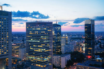 Illuminated buildings in city against sky at dusk