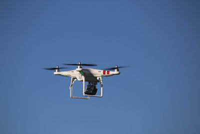 Low angle view of airplane flying against clear blue sky