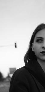 Portrait of young woman standing against clear sky