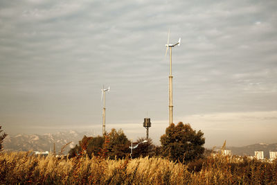 Windmill on field against cloudy sky