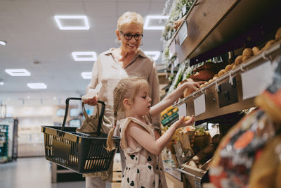 Side view of girl buying groceries with grandmother at store