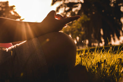 Midsection of person on field against sky during sunset