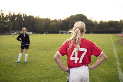 Rear view of girl standing on soccer field