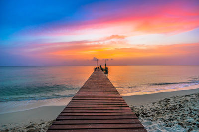 High angle view of pier on sandy beach during sunset