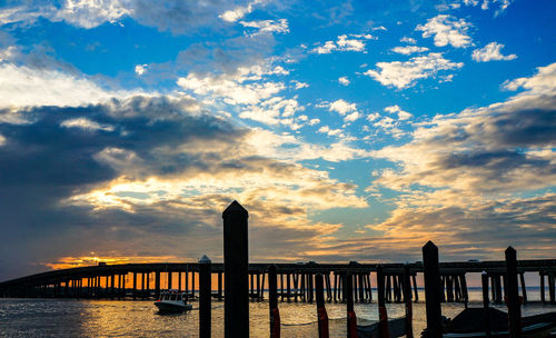 Silhouette pier over sea against sky during sunset