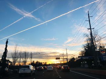 Cars on road against sky at sunset