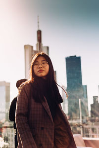 Portrait of woman standing against buildings in city