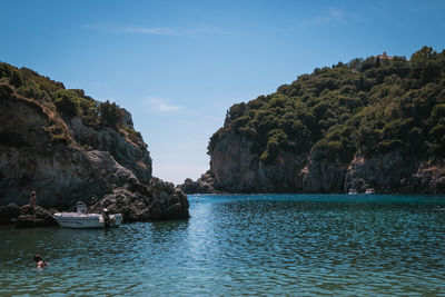 Scenic view of sea by mountains against sky