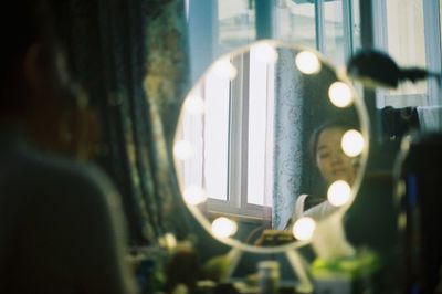 Reflection of woman in illuminated mirror
