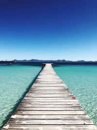 Pier over sea against clear blue sky